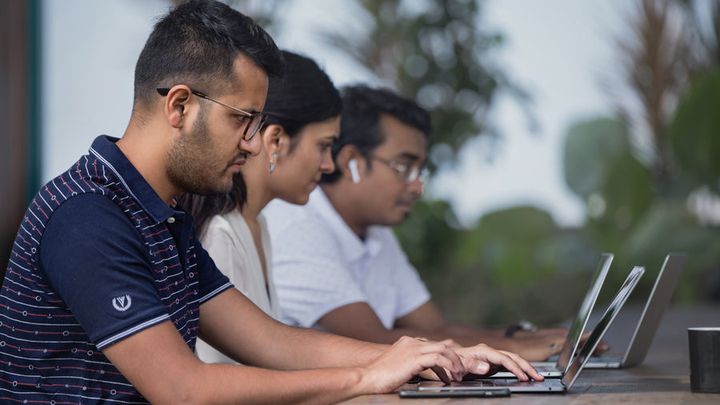 Three colleagues working side by side on laptops