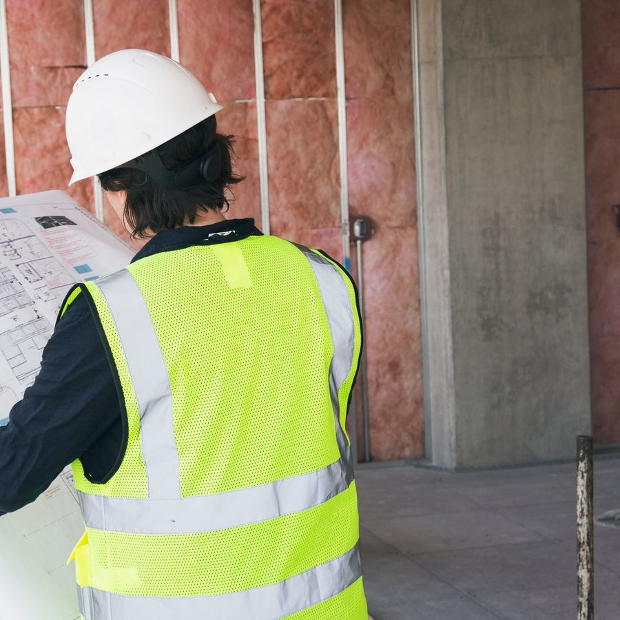 A site worker in a high-visibility vest reading drawings on a construction site