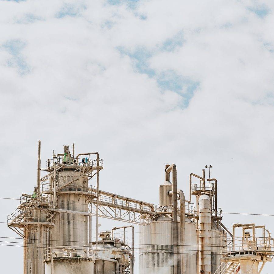 Silos and pipework at an industrial process plant under a bright sky