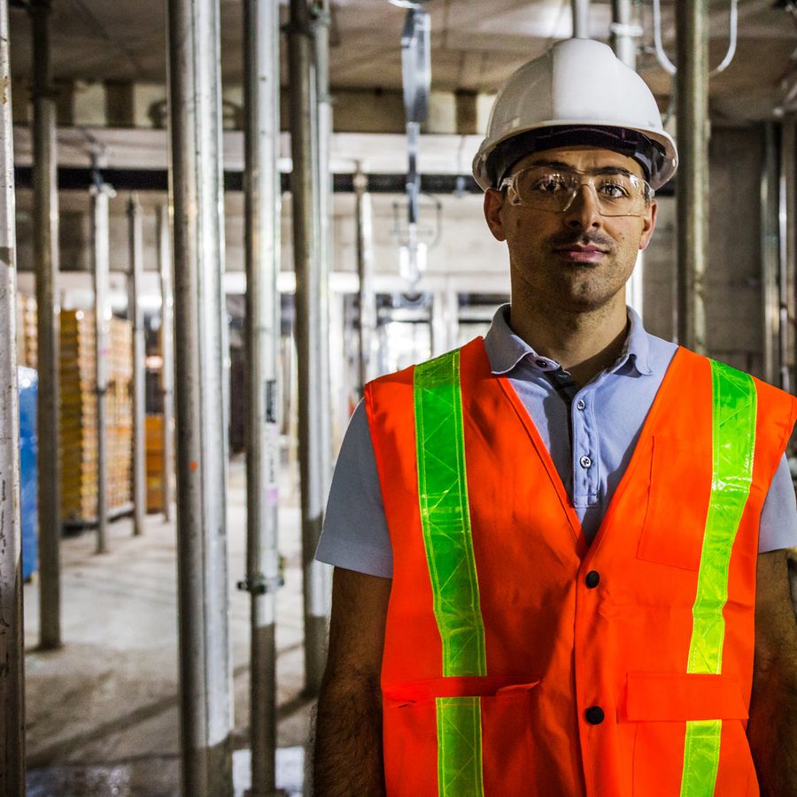 A production worker in a hard hat and high-visibility vest on a factory floor
